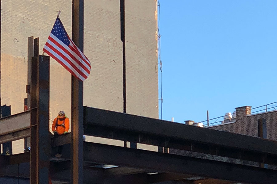 Picture of a job site with a construction worker and the United States flag | Independence Day | Knowify